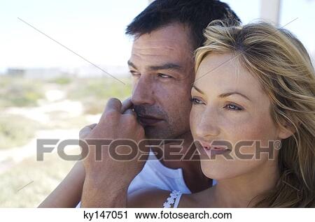 Stock Image - Portrait of embracing couple daydreaming. Fotosearch