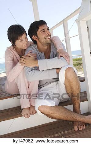 Smiling couple sitting on wooden terrace View Large Photo Image Stock Image - Smiling couple sitting on wooden terrace. Fotosearch
