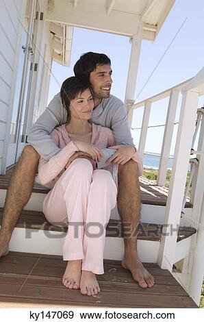 Smiling couple sitting on wooden terrace View Large Photo Image Stock Photo - Smiling couple sitting on wooden terrace. Fotosearch