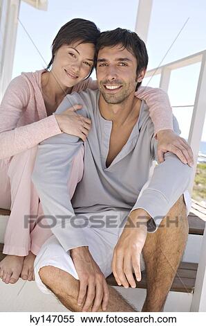 Stock Photography - Smiling couple sitting on wooden terrace. Fotosearch