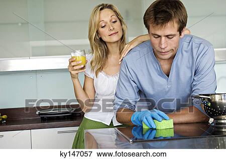 Young woman laughing at man using sponge in kitchen View Large Photo Image Stock Photo - Young woman laughing at man using sponge in kitchen. Fotosearch