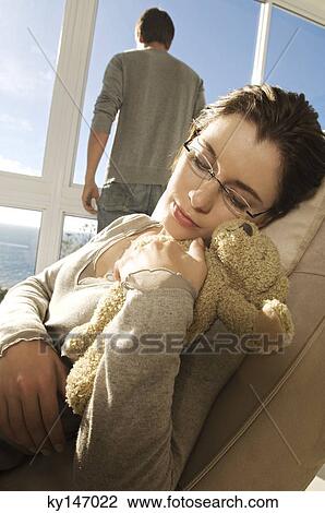 Young woman sleeping with teddy bear, man in background View Large Photo Image Stock Image - Young woman sleeping with teddy bear, man in background. Fotosearch