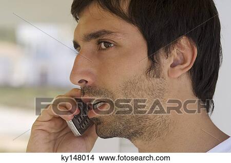 Portrait of a young man using mobile phone View Large Photo Image Picture - Portrait of a young man using mobile phone. Fotosearch