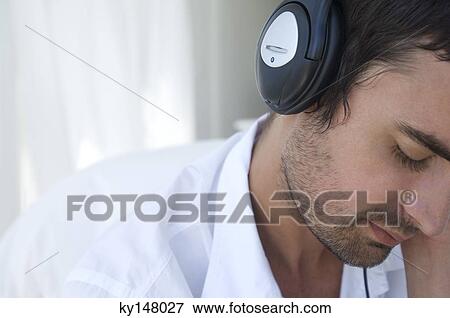 Portrait of young man listening to music with headphones View Large Photo Image Stock Photo - Portrait of young man listening to music with headphones. Fotosearch