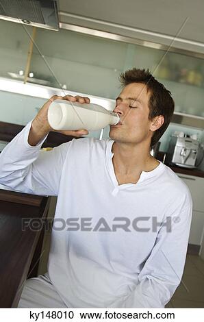Stock Image - Young man drinking milk from a bottle. Fotosearch