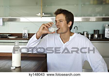 Young man drinking milk in kitchen View Large Photo Image Stock Image - Young man drinking milk in kitchen. Fotosearch