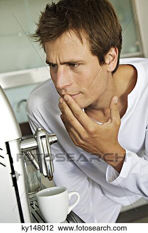 Stock Image - Young man in front of espresso maker. Fotosearch
