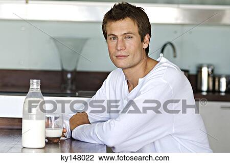 Young man in kitchen, holding glass of milk View Large Photo Image Stock Image - Young man in kitchen, holding glass of milk. Fotosearch