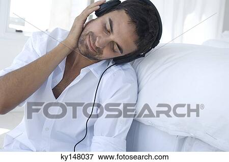 Young man listening to music with headphones View Large Photo Image Stock Photo - Young man listening to music with headphones. Fotosearch