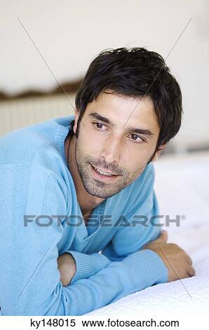 Young man lying on bed View Large Photo Image Stock Photography - Young man lying on bed. Fotosearch