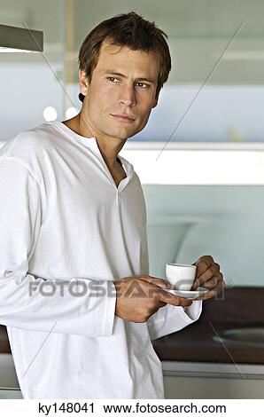 Young thinking man in kitchen, holding coffee cup View Large Photo Image Stock Image - Young thinking man in kitchen, holding coffee cup. Fotosearch