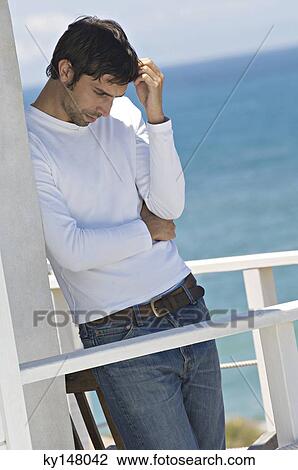 Young thinking man leaning against wall on a terrace, sea in background View Large Photo Image Stock Image - Young thinking man leaning against wall on a terrace, sea in background. Fotosearch