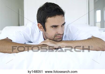 Young thinking man lying on bed View Large Photo Image Stock Image - Young thinking man lying on bed. Fotosearch