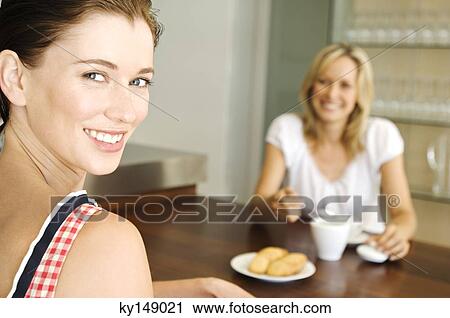 2 smiling women sitting at table View Large Photo Image Stock Image - 2 smiling women sitting at table. Fotosearch