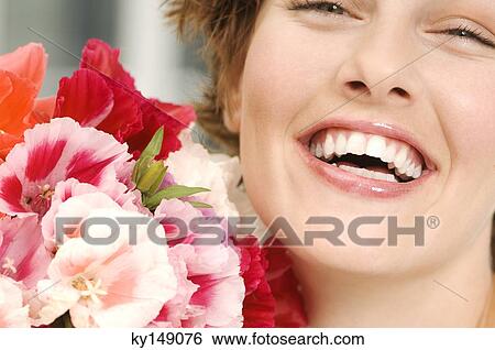Stock Photograph - Portrait of smiling woman holding bunch of flowers. Fotosearch