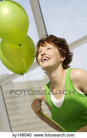 Portrait of young smiling woman holding green balloons View Large Photo Image Stock Image - Portrait of young smiling woman holding green balloons. Fotosearch