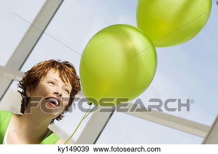 Portrait of young smiling woman holding green balloons View Large Photo Image Stock Photo - Portrait of young smiling woman holding green balloons. Fotosearch