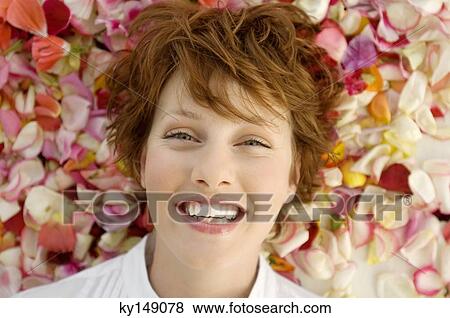 Portrait of young smiling woman, lying on flowers petals View Large Photo Image Stock Photo - Portrait of young smiling woman, lying on flowers petals. Fotosearch