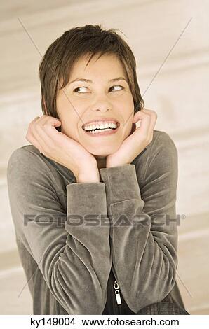 Portrait of young smiling woman, looking away, hands on chin View Large Photo Image Picture - Portrait of young smiling woman, looking away, hands on chin. Fotosearch