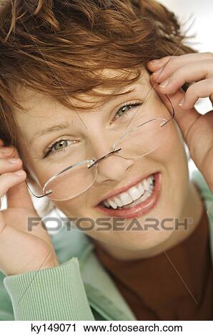 Portrait of young smiling woman putting her eye glasses on View Large Photo Image Stock Image - Portrait of young smiling woman putting her eye glasses on. Fotosearch