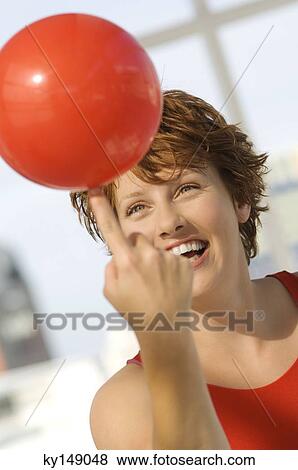 Portrait of young woman balancing red balloon on her finger View Large Photo Image Stock Photo - Portrait of young woman balancing red balloon on her finger. Fotosearch