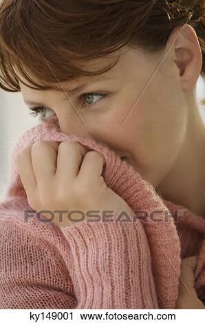 Portrait of young woman covering her mouth with jumper View Large Photo Image Stock Image - Portrait of young woman covering her mouth with jumper. Fotosearch