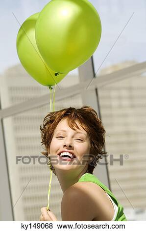 Portrait of young woman holding green balloons View Large Photo Image Stock Photo - Portrait of young woman holding green balloons. Fotosearch