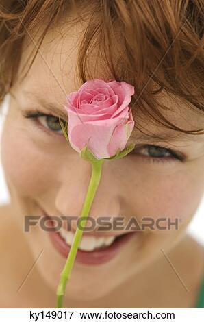 Portrait of young woman with rose in front of face View Large Photo Image Stock Photo - Portrait of young woman with rose in front of face. Fotosearch