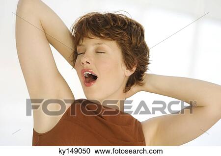 Portrait of young woman yawning, hands behind head View Large Photo Image Stock Image - Portrait of young woman yawning, hands behind head. Fotosearch
