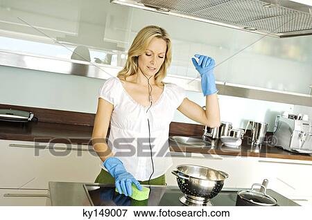 Young woman cleaning kitchen while listening to music View Large Photo Image Stock Photo - Young woman cleaning kitchen while listening to music. Fotosearch