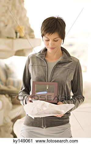 Stock Image - Young woman holding box. Fotosearch