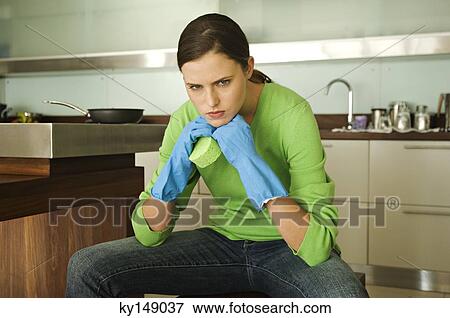 Stock Photo - Young woman looking angry in kitchen. Fotosearch