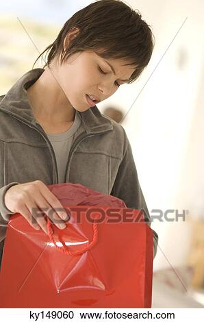 Young woman opening bag, looking disappointed View Large Photo Image Stock Image - Young woman opening bag, looking disappointed. Fotosearch