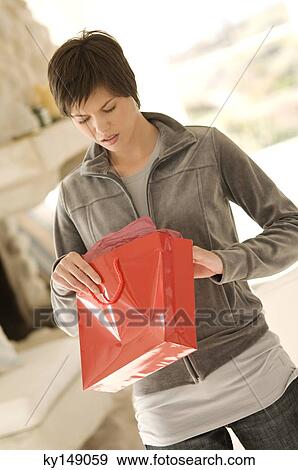 Young woman opening bag, looking disappointed View Large Photo Image Stock Photo - Young woman opening bag, looking disappointed. Fotosearch