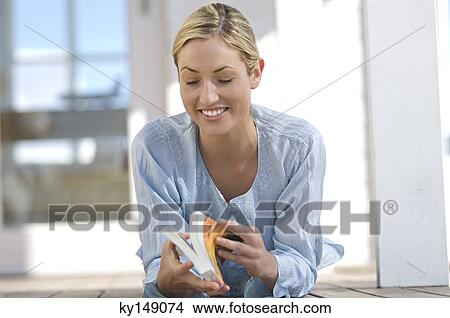 Young woman reading a book, lying on terrace View Large Photo Image Picture - Young woman reading a book, lying on terrace. Fotosearch