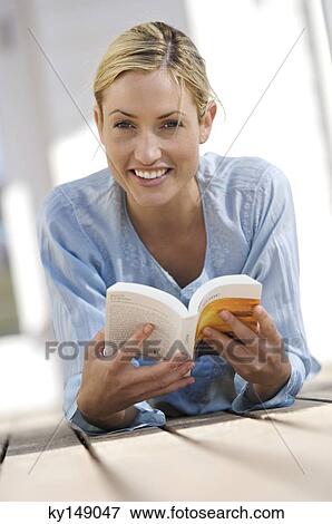 Young woman reading a book, lying on terrace View Large Photo Image Stock Photo - Young woman reading a book, lying on terrace. Fotosearch