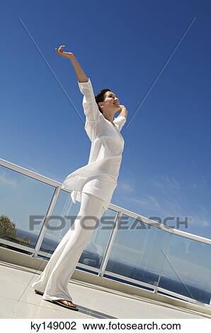 Stock Image - Young woman stretching on terrace. Fotosearch