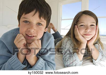 Boy and girl lying on bed View Large Photo Image Stock Image - Boy and girl lying on bed. Fotosearch