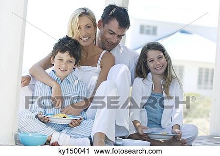 Couple and two children eating, sitting on wooden terrace View Large Photo Image Stock Image - Couple and two children eating, sitting on wooden terrace. Fotosearch