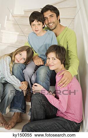Couple and two children smiling for the camera, sitting on stairs View Large Photo Image Stock Photography - Couple and two children smiling for the camera, sitting on stairs. Fotosearch
