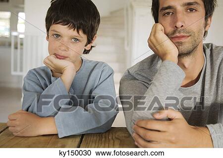 Father and son looking at camera, with hands on chins View Large Photo Image Stock Image - Father and son looking at camera, with hands on chins. Fotosearch