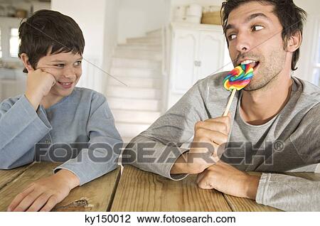 Father eating lollipop with his son View Large Photo Image Stock Image - Father eating lollipop with his son. Fotosearch
