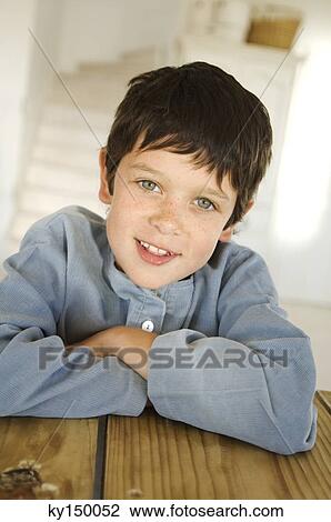 Little boy smiling for the camera, resting on table View Large Photo Image Stock Image - Little boy smiling for the camera, resting on table. Fotosearch