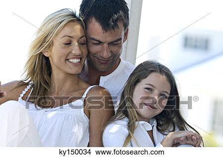 Parents and daughter smiling for the camera, outdoors View Large Photo Image Picture - Parents and daughter smiling for the camera, outdoors. Fotosearch