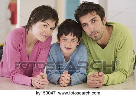 Parents and son looking at camera, lying on floor View Large Photo Image Stock Photo - Parents and son looking at camera, lying on floor. Fotosearch