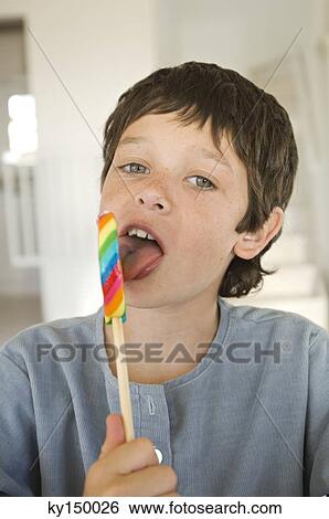 Stock Photograph - Portrait of little boy licking lollipop. Fotosearch