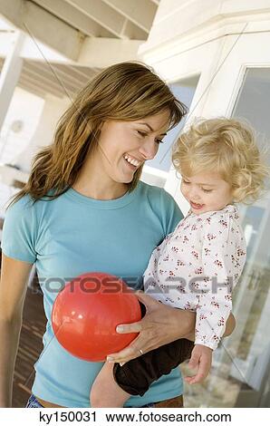 Stock Image - Smiling woman carrying little girl. Fotosearch