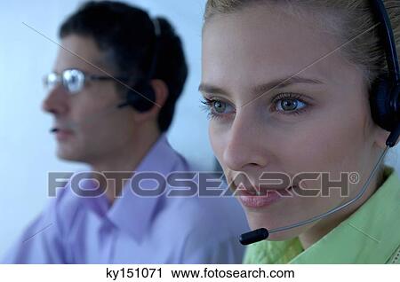 Stock Image - Businessman and businesswoman wearing headset. Fotosearch