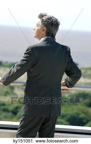 Mature businessman standing in balcony View Large Photo Image Stock Image - Mature businessman standing in balcony. Fotosearch