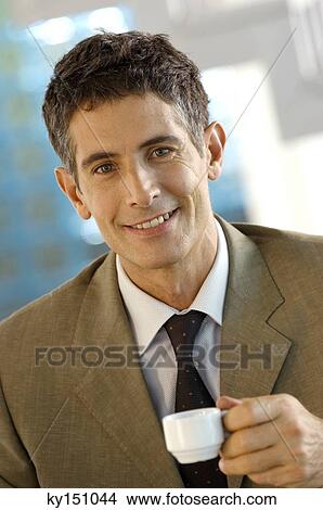 Mid adult businessman holding cup of coffee, portrait View Large Photo Image Picture - Mid adult businessman holding cup of coffee, portrait. Fotosearch